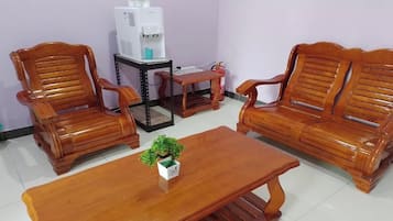 A room with two wooden sofas, a wooden coffee table, and a small table with a water dispenser.