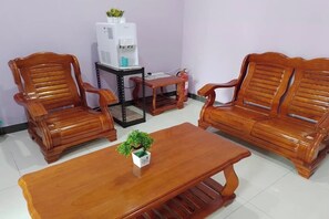 Una habitación con dos sofás de madera, una mesa de centro de madera y una pequeña mesa con dispensador de agua.