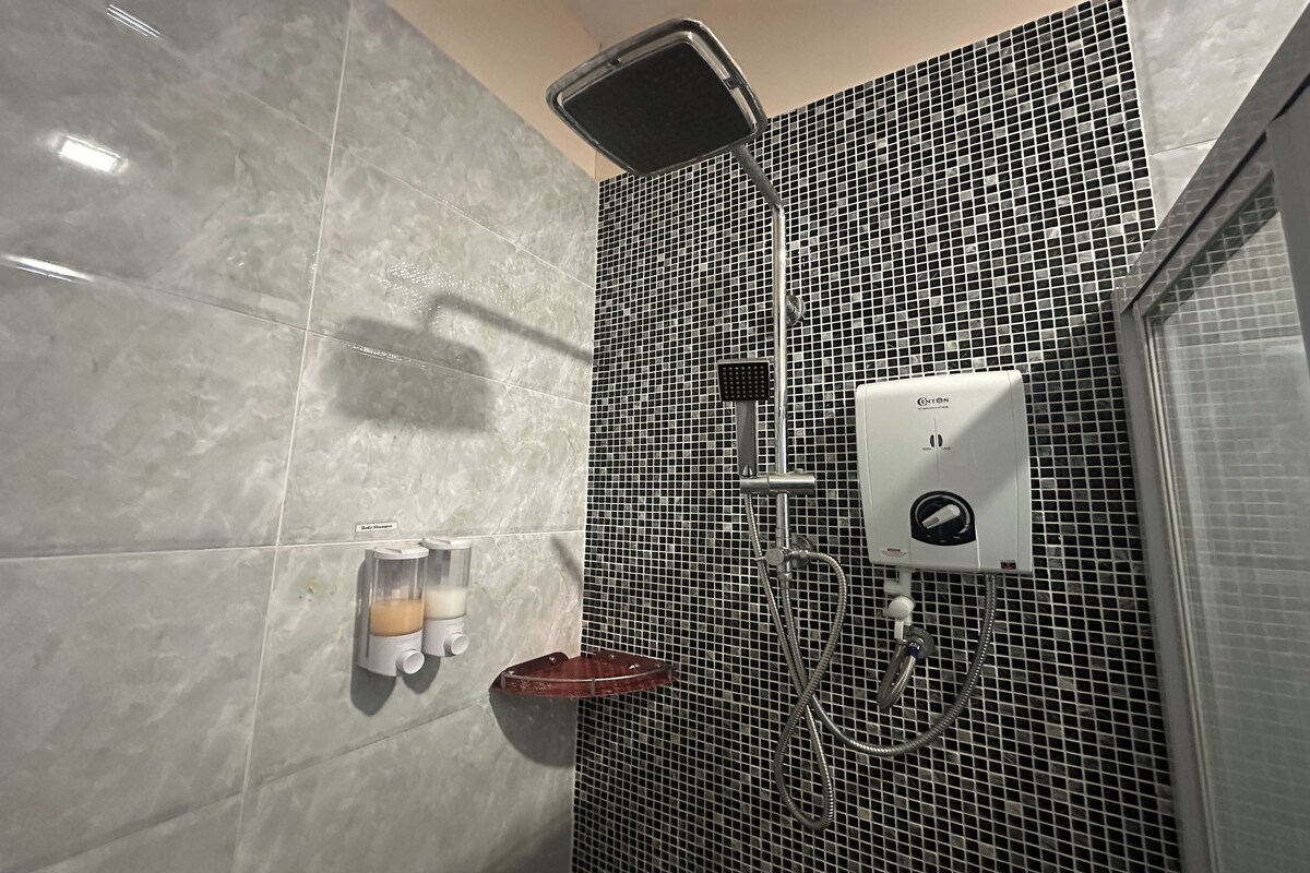 Un baño con ducha, dispensador de jabón y secador de manos.