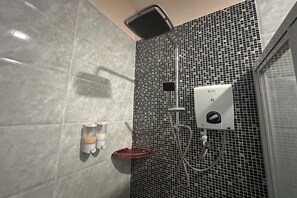 Un bagno con doccia, un erogatore di sapone e un asciugamani ad aria.