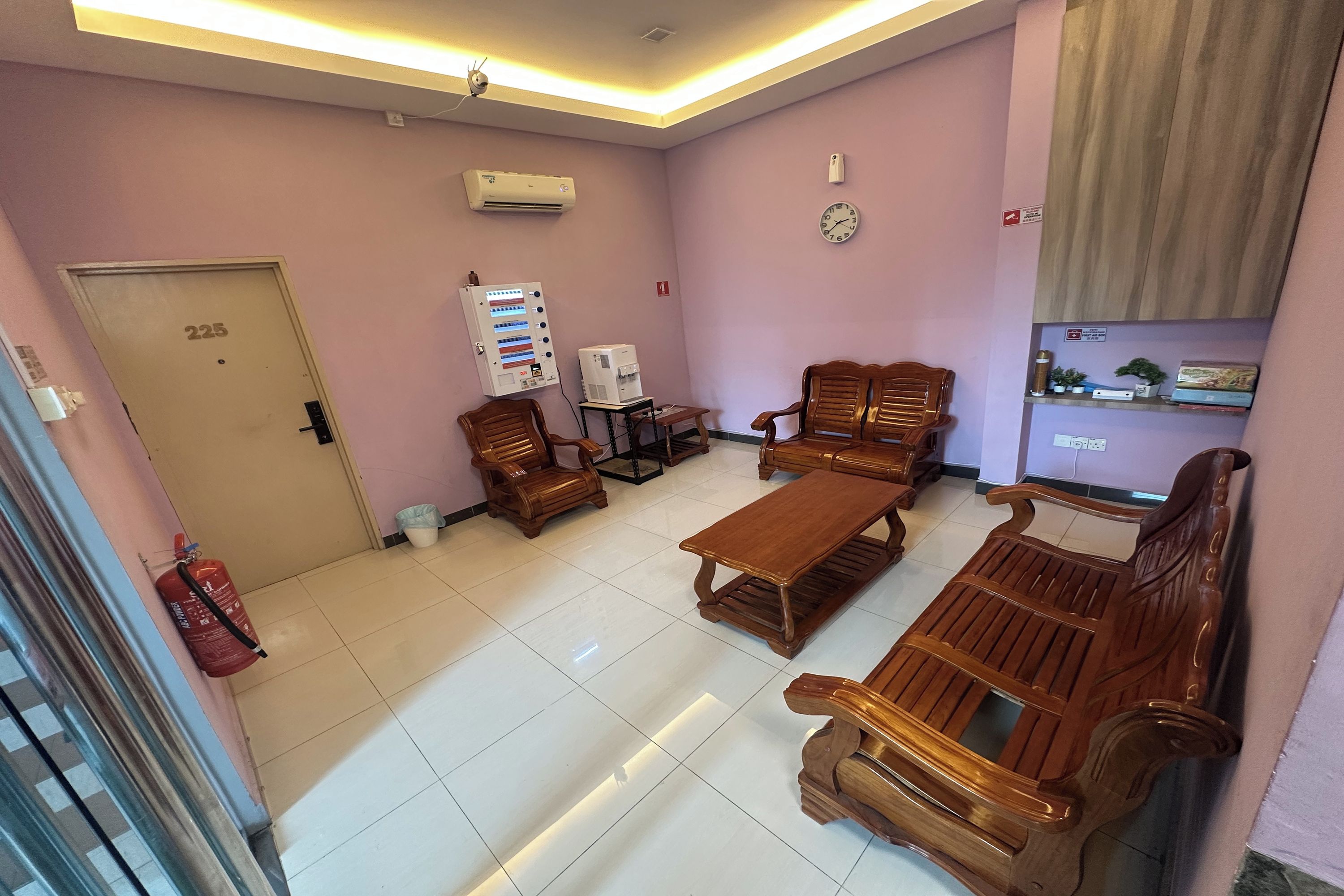 A hotel lobby with a reception desk, wooden furniture, and a clock on the wall.