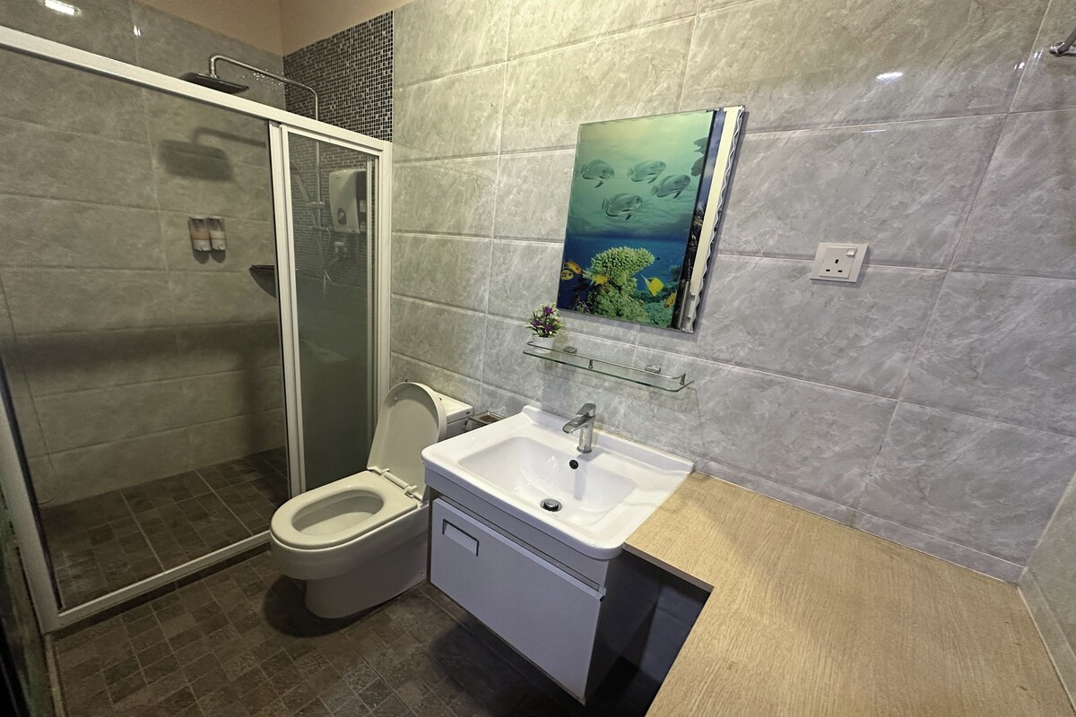 A bathroom with a glass-enclosed shower, a toilet, and a sink with a mirror above it.