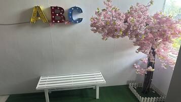 A white bench, a wall with illuminated letters ABC, and a cherry blossom tree.