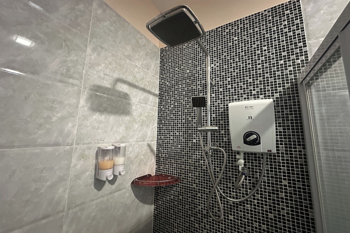 A bathroom with a shower, a soap dispenser, and a hand dryer.