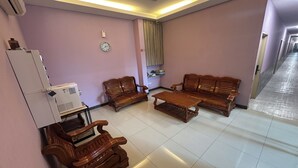 Una sala de estar con muebles de madera, piso de baldosas blancas y un reloj en la pared.