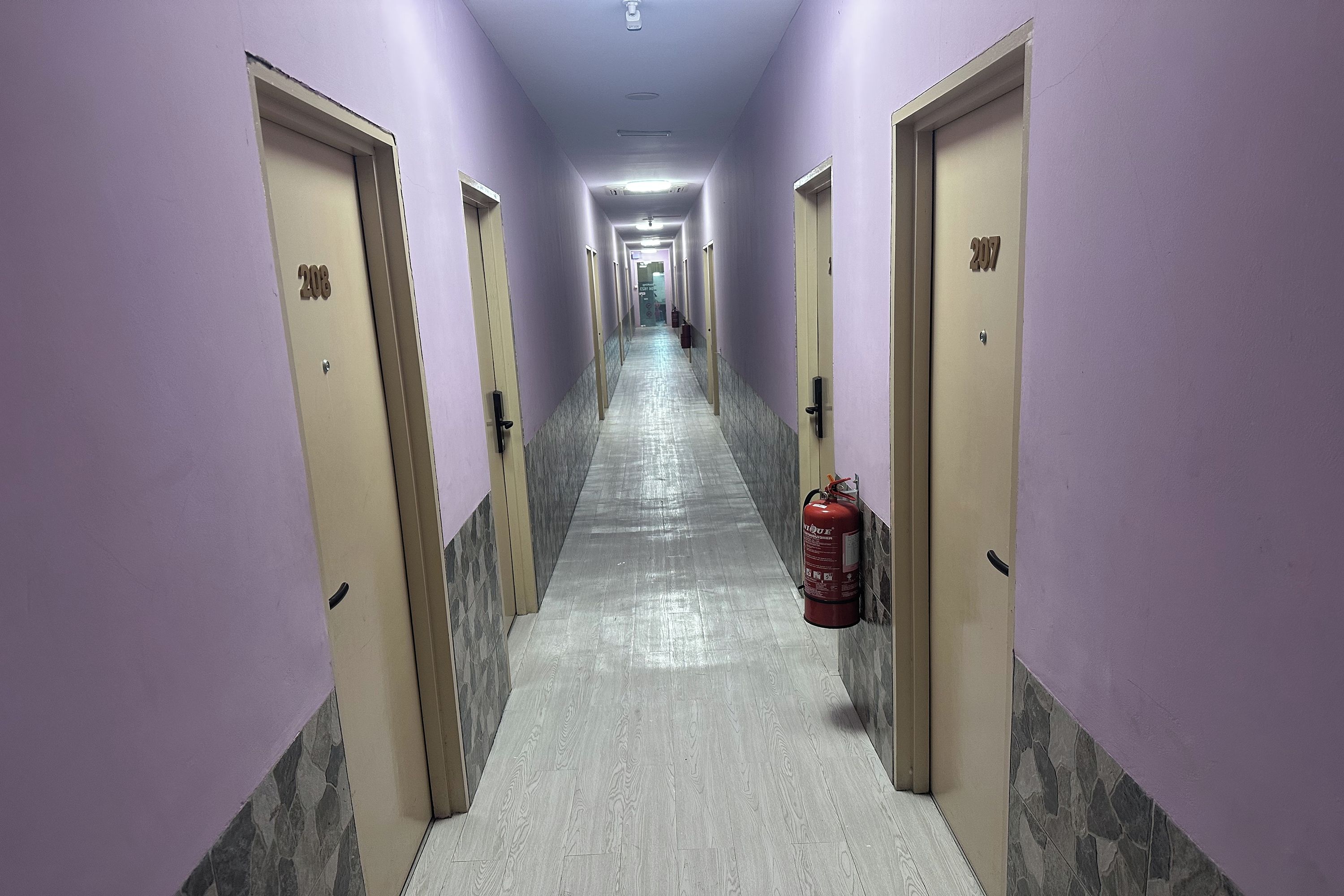 A hallway with doors numbered 200 and 207, a fire extinguisher, and a tiled floor.