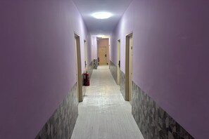 Un pasillo con paredes moradas, suelo de baldosas y puertas a ambos lados.
