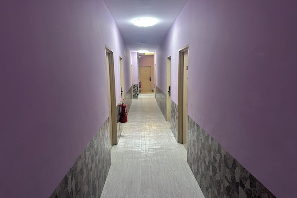 A hallway with purple walls, a tiled floor, and doors on both sides. - Abc Hostel By Zuzu (Seri Kembangan)