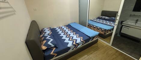 Quarto pequeno com cama, armário e espelho.