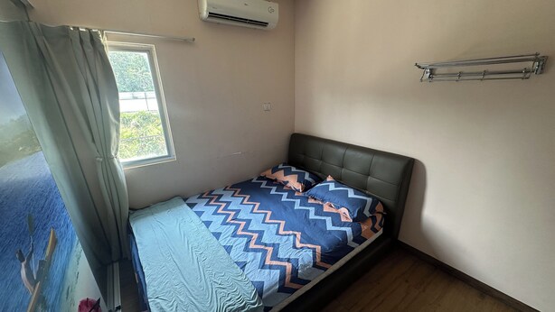 A single bed with a patterned bedspread, a window with curtains, an air conditioning unit, and a metal towel rack. - Abc Hostel By Zuzu (Seri Kembangan)