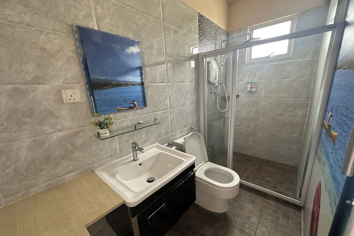 A bathroom with a sink, toilet, and glass shower enclosure.