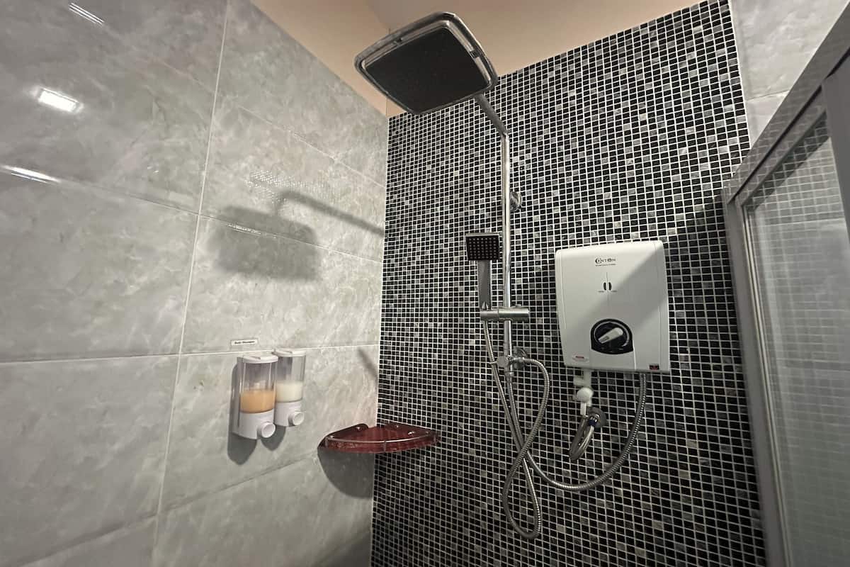 Een badkamer met een douche, een zeepdispenser en een handdroger.