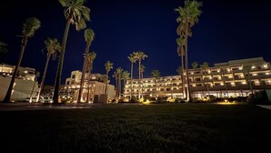 A hotel with multiple floors, palm trees, and well-lit surroundings. - Punta Bermeja Premium Beach Hotel (El Puerto de Santa Maria)