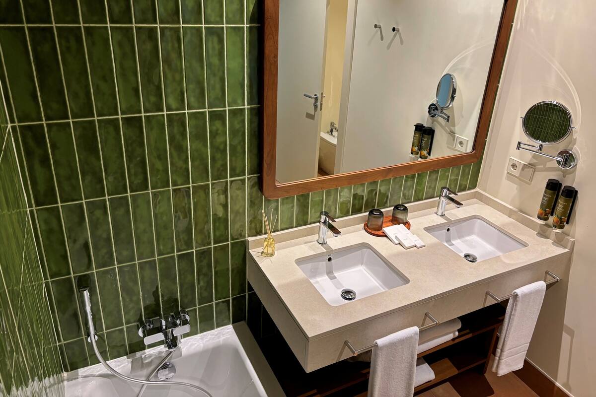 Ein Badezimmer mit zwei Waschbecken, einem großen Spiegel und einer Badewanne.