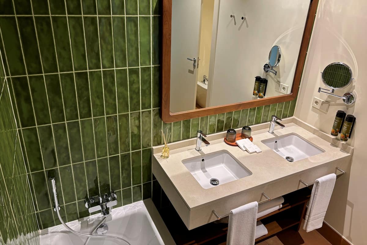 Une salle de bain avec deux lavabos, un grand miroir et une baignoire.