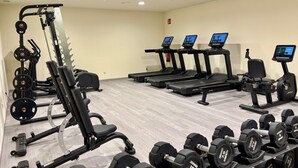 Un gimnasio con equipo de ejercicio variado, incluyendo cintas de correr, máquinas de pesas y mancuernas.