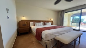 Ein Hotelzimmer mit einem großen Bett, einem Nachttisch, einer Bank und Blick ins Freie.