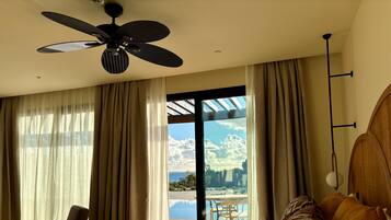 A hotel room with a bed, a chair, a ceiling fan, and a view of the outdoors.