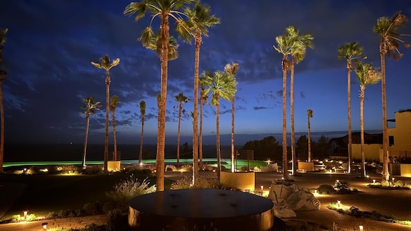 Ein Nachtblick auf ein Resort mit Palmen, einem Pool und einem gut beleuchteten Weg.