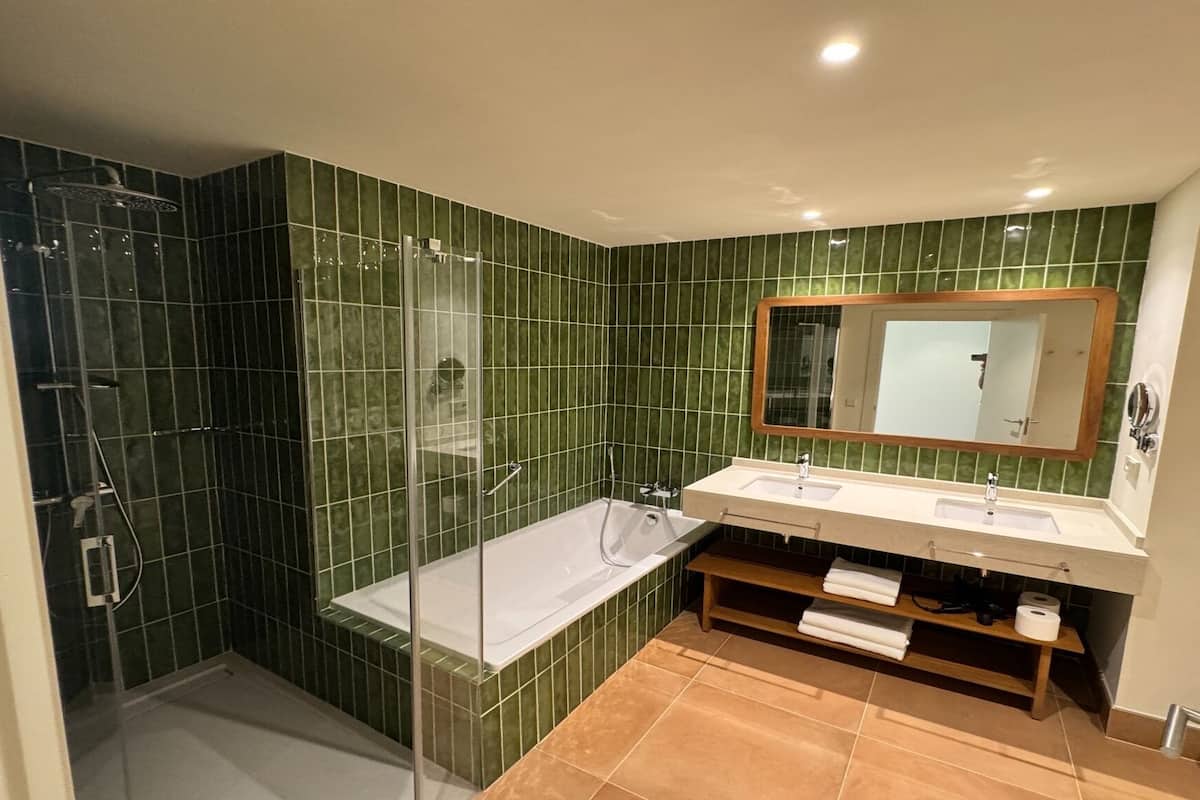 Ein Badezimmer mit Duschkabine, einer weißen Badewanne und einem Waschtisch mit zwei Becken.