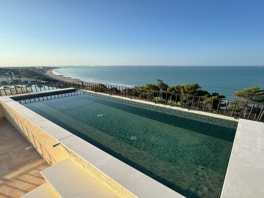 Piscina infinita en la azotea con vistas despejadas al océano y la playa.