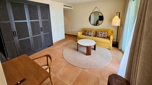 Una sala de estar con sofá, mesa de centro, alfombra redonda y mesa de comedor.
