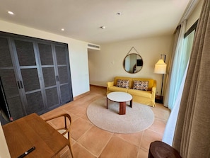 A living room with a sofa, a coffee table, a round rug, and a dining table. - Punta Bermeja Premium Beach Hotel (El Puerto de Santa Maria)