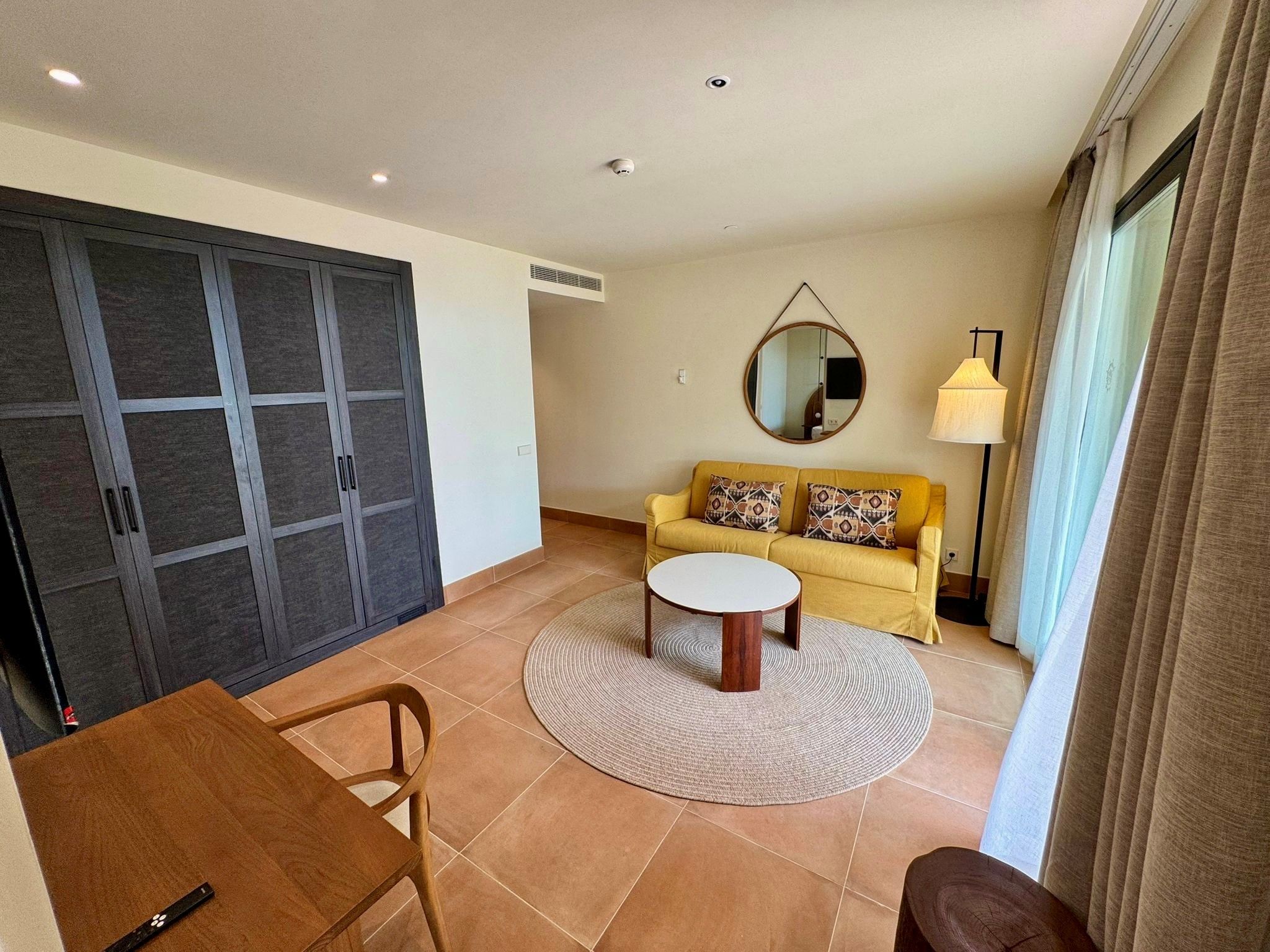 A living room with a sofa, a coffee table, a round rug, and a dining table.