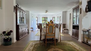 Un comedor espacioso con una gran mesa, varias sillas y vistas al exterior a través de amplios ventanales.