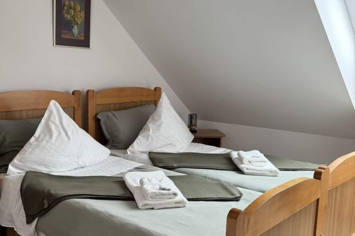 A double bed with two pillows, a bedside table, and a framed picture on the wall.