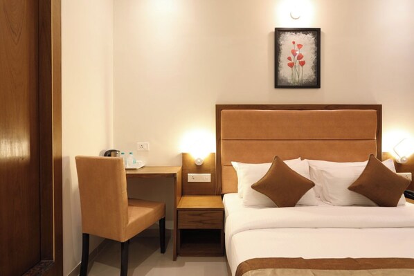 A hotel room with a bed, bedside table, chair, and a painting on the wall. - Hotel The Azure (Mumbai)