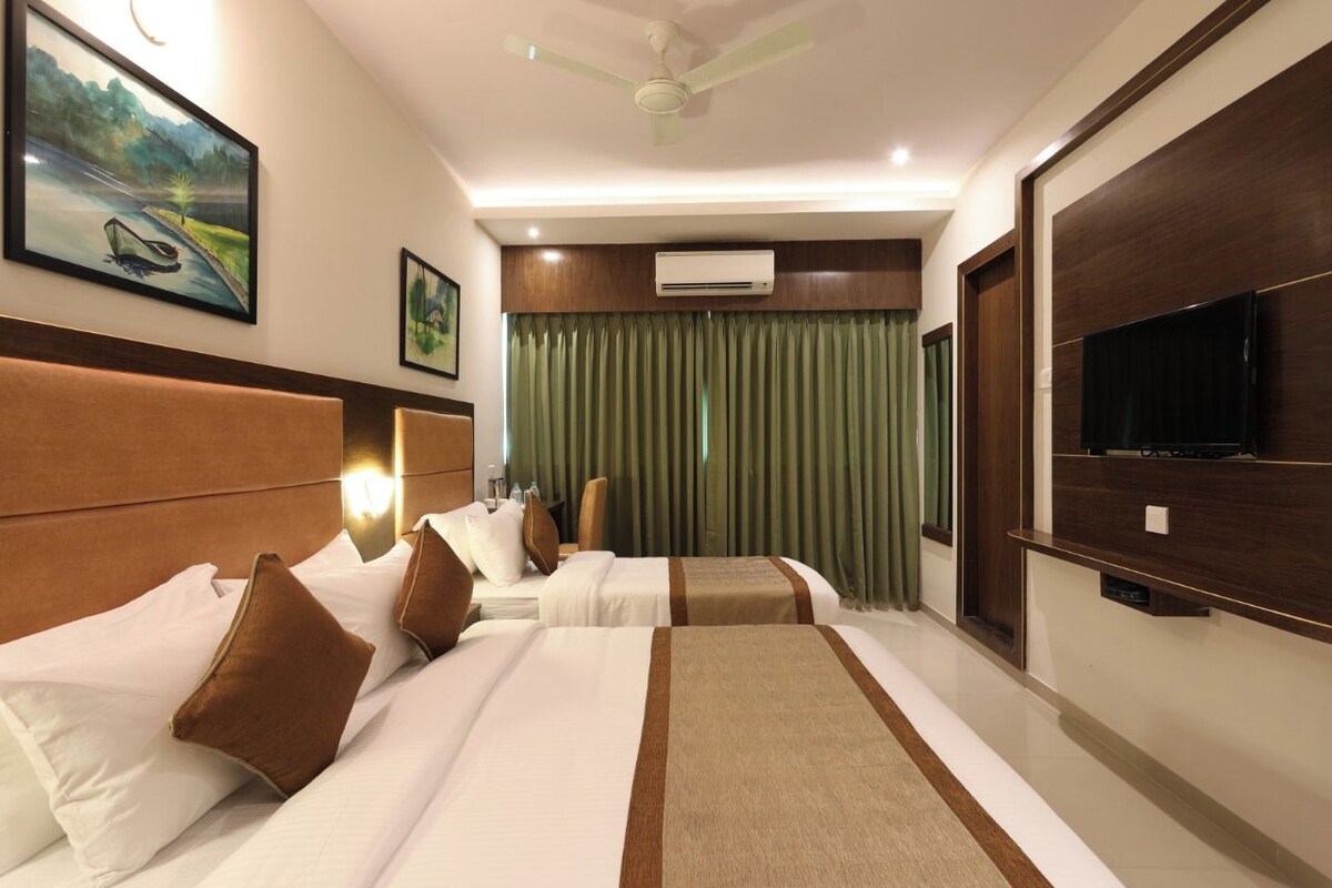 A hotel room with two beds, a flat-screen TV, an air conditioning unit, and a ceiling fan.