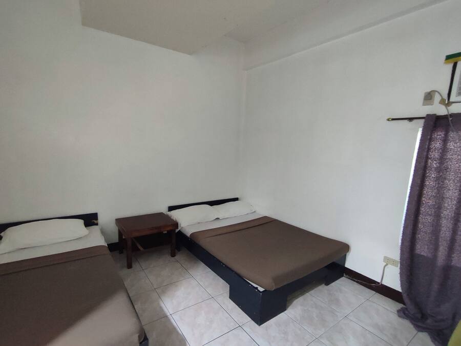 A room with two single beds, a small table, and a curtain.