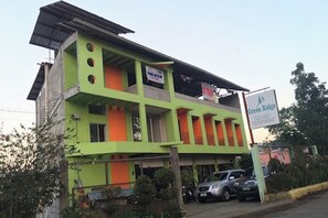 Un edificio de varios pisos con fachada verde y naranja, un letrero que dice 'Green Ridge' y un coche estacionado al frente.