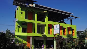 Un edificio de dos plantas con fachada verde y naranja, un letrero que dice "Green Ridge" y un área de entrada cubierta.