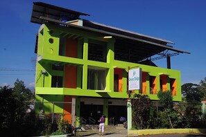 A two-story building with a green and orange facade, a sign reading "Green Ridge," and a covered entrance area. - Green Ridge Apartelle By Zuzu (Malaybalay City)