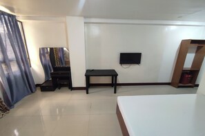 A bedroom with a bed, a desk, a chair, a television, and a wardrobe. - Green Ridge Apartelle By Zuzu (Malaybalay City)