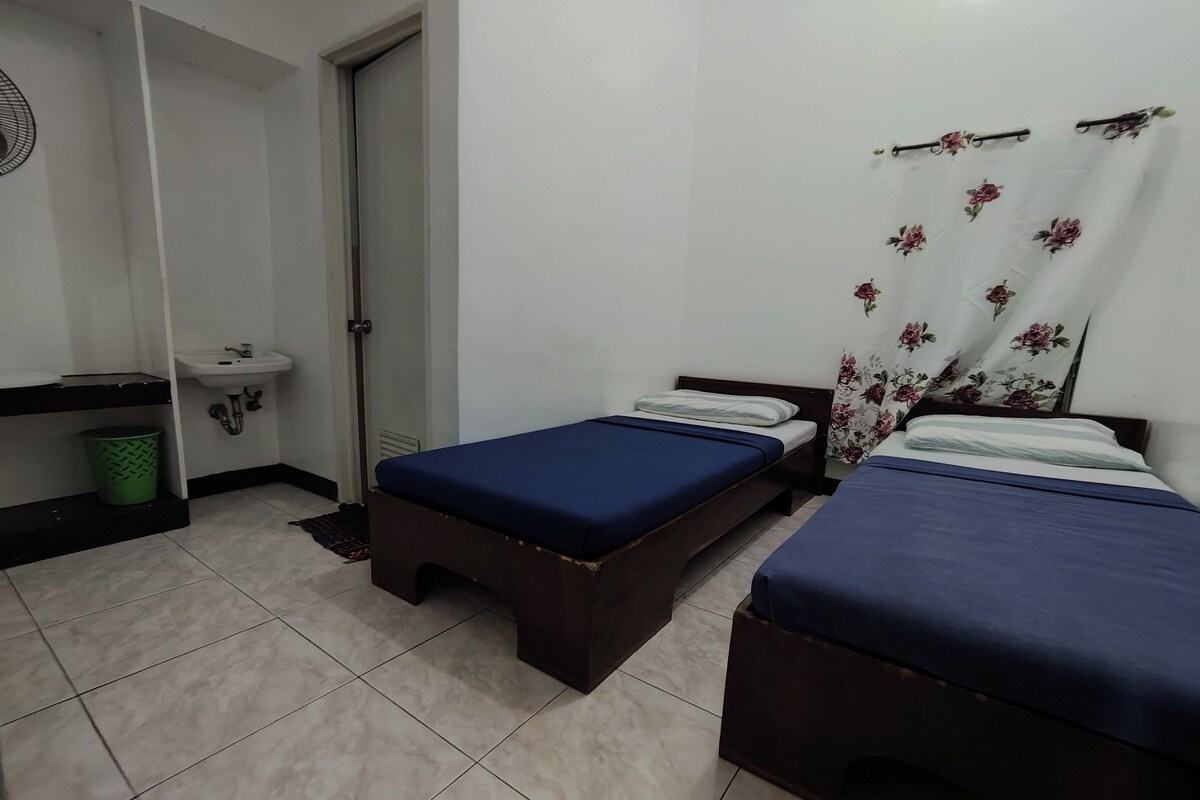 A room with two beds, a sink, and a door.
