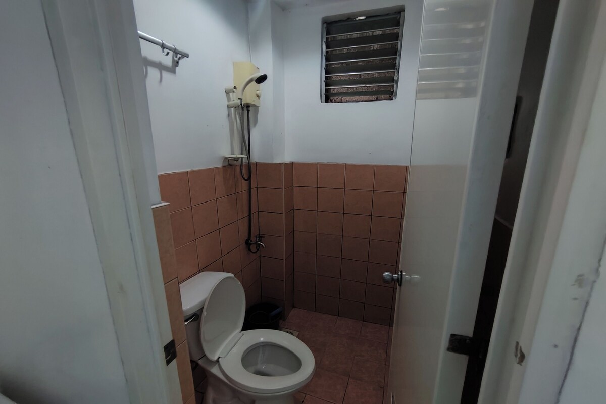 Un baño pequeño y funcional con inodoro, ducha y una ventana pequeña.