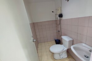 A small bathroom with a toilet, a sink, and a shower. - Green Ridge Apartelle By Zuzu (Malaybalay City)