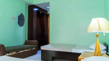 A room with a bed, a small sofa, a nightstand, and a lamp.