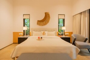 A hotel room with a large bed, two bedside tables with lamps, a chair, and a wall-mounted decorative piece. - Elivaas Shai - Goa (Assagao)