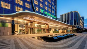 A modern hotel with a curved facade, illuminated signage, and a water feature in front. - Holiday Inn Fuzhou Exhibition Center (Fuzhou)