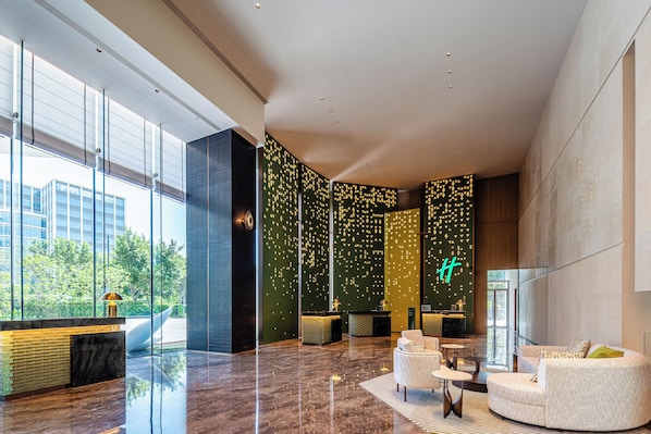 Un vestíbulo moderno con una recepción, zona de estar y ventanas amplias que ofrecen vistas al paisaje verde.