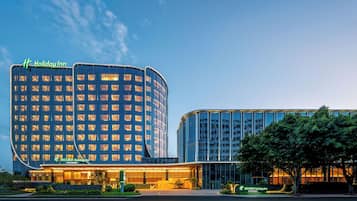 A modern Holiday Inn hotel with a curved facade, large windows, and a well-lit entrance.