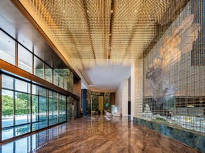 A spacious lobby with a reflective marble floor, large windows offering a view of greenery, and a ceiling adorned with hanging lights. - Holiday Inn Fuzhou Exhibition Center (Fuzhou)