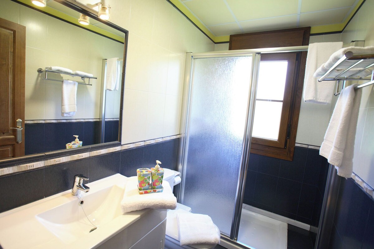 A bathroom with a white sink, a mirror, a shower, and a towel rack.