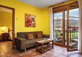 Una habitación con sofá, una mesa, un cuadro y puerta corrediza de vidrio a un espacio exterior.
