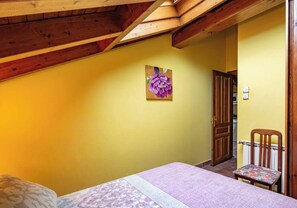 A bedroom with a bed, a chair, a door, and a painting on the wall.