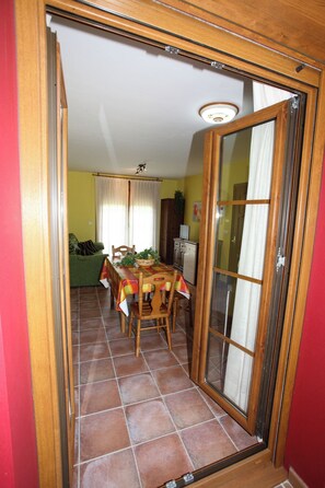A dining area with a table set for four, a green sofa, and a kitchen in the background. - Apartamentos Rurales La Viña (Cangas de Onis)